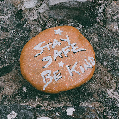 A rock with the words "stay safe, be kind" painted on it