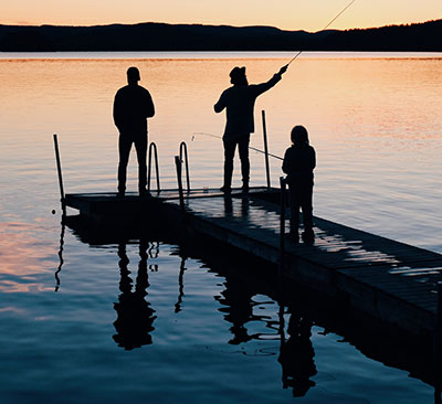 Family fishing on a dock at sunset.