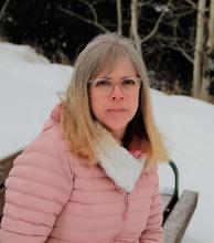 Blonde woman in pink coat smiling against snowy background